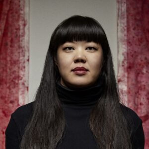 jen's headshot against a backdrop consisting of two red vertical brushsrokes to either side of a grey surface